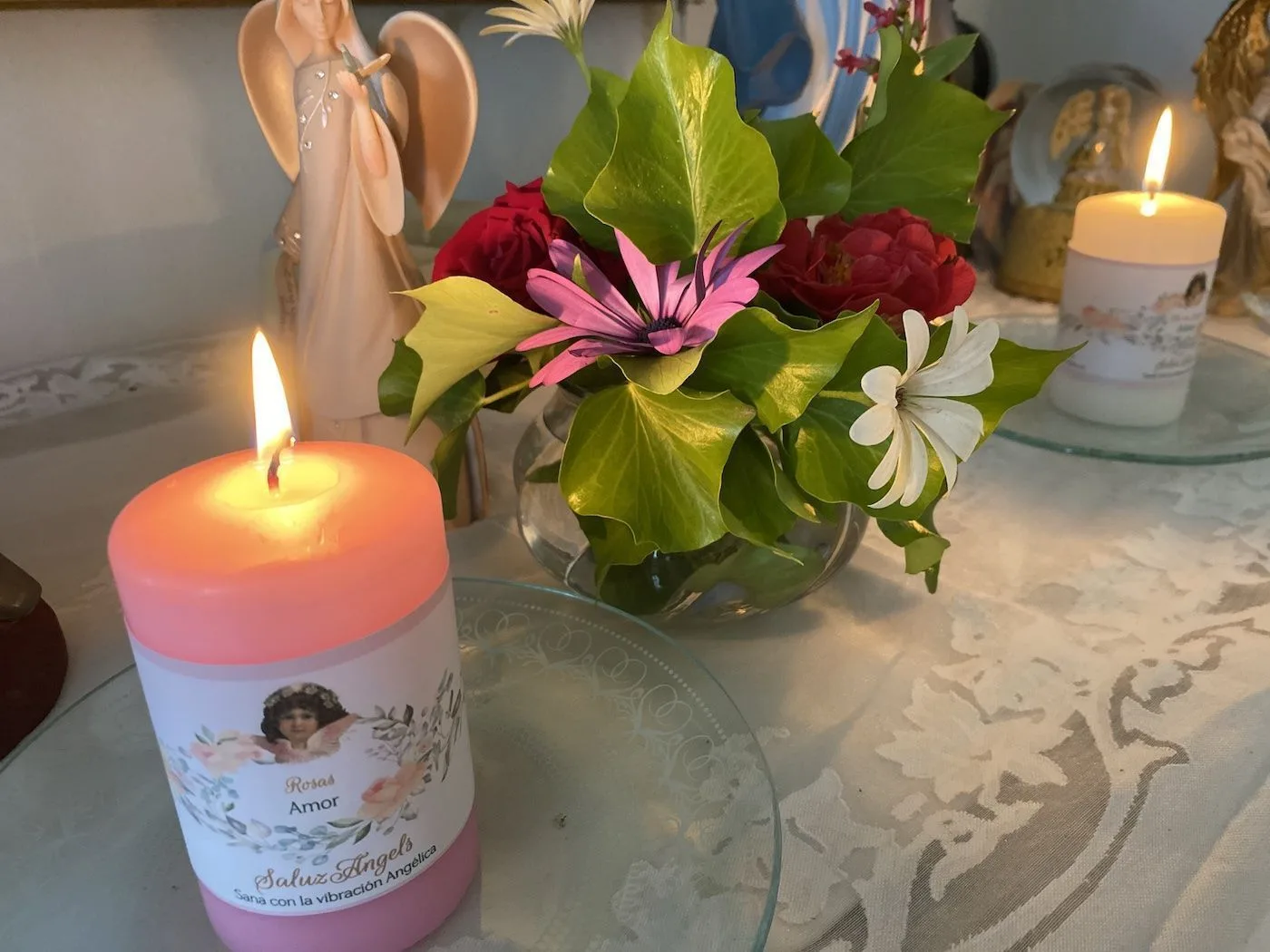 Vela encendida y flores frescas para una limpieza energética con ángeles